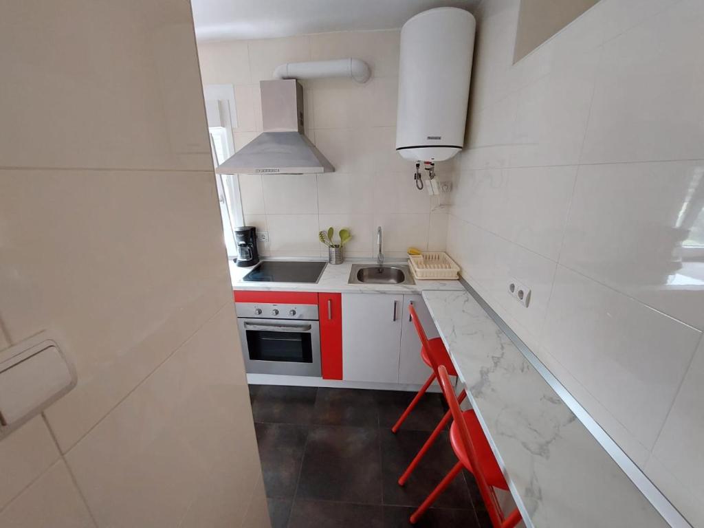 una pequeña cocina blanca con fregadero y fogones en Apartamento parque las llamas, en Santander
