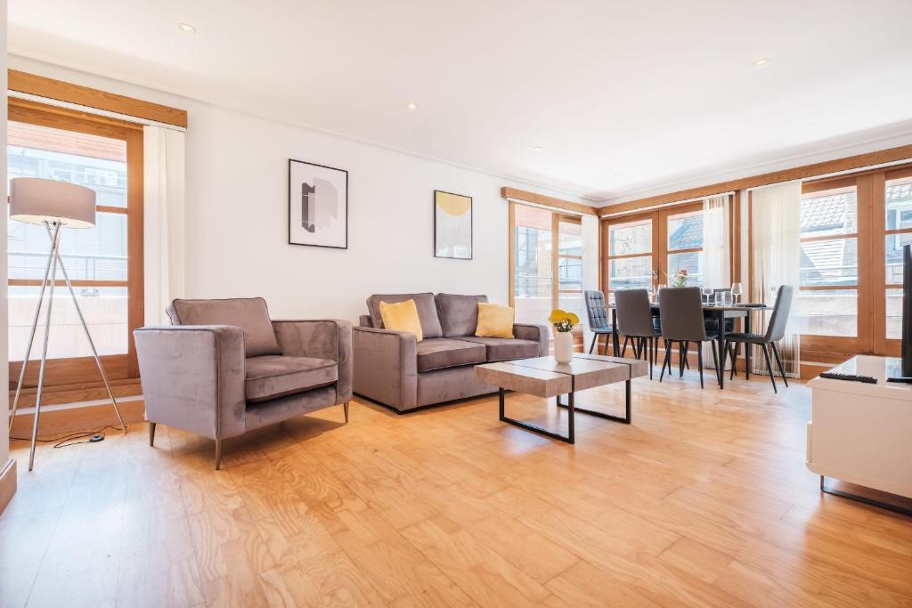un soggiorno con divano, sedie e tavolo di 2BR Penthouse with Terrace - Heart of Holborn - CityApartmentStay a Londra