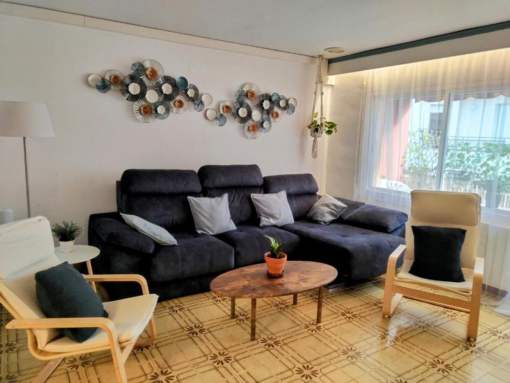 sala de estar con sofá azul y sillas en Spacious family flat centrally located., en Palamós