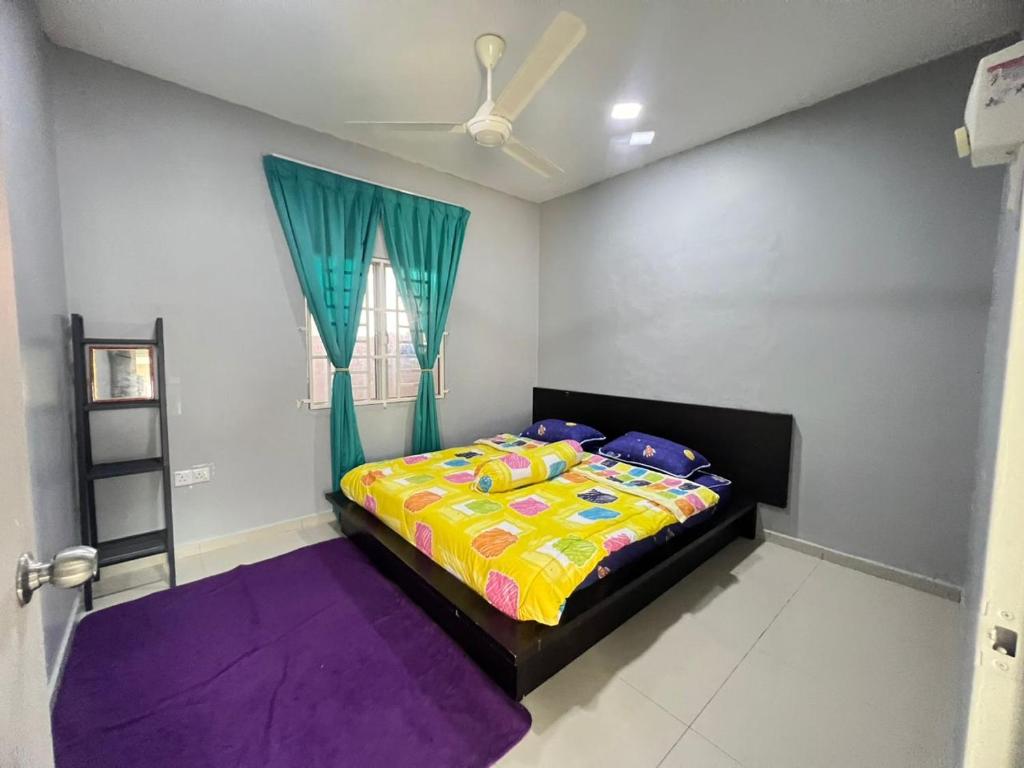 a bedroom with a bed with a colorful comforter and a window at Homestay Murah SemiD in Kampong Badak