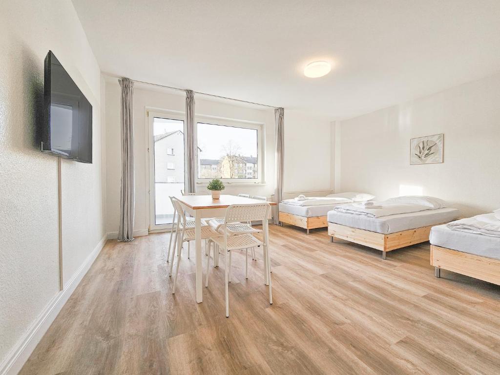 a room with two beds and a table and chairs at RAJ Living - 2 Zimmer Wohnungen mit Balkon - 25 Min zur Messe DUS in Heiligenhaus