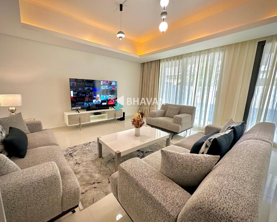a living room with a couch and a tv at Calm Chaos 4 BR Villa with maid Room in Damac Hills 2 in Dubai