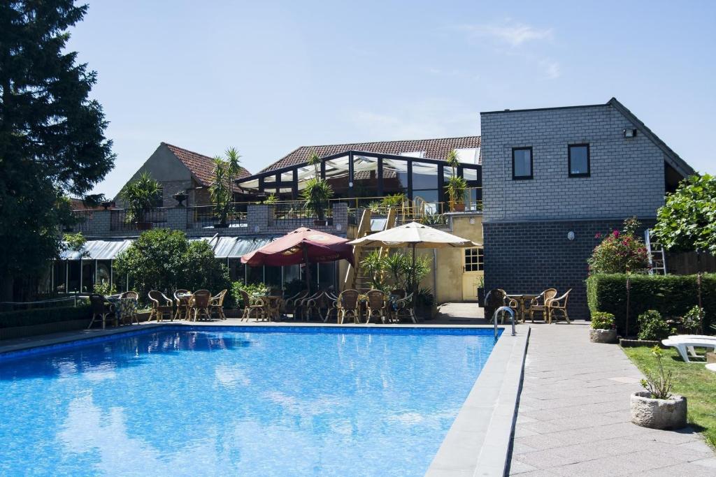 a swimming pool with chairs and umbrellas next to a building at Hotel Pacific in Weelde