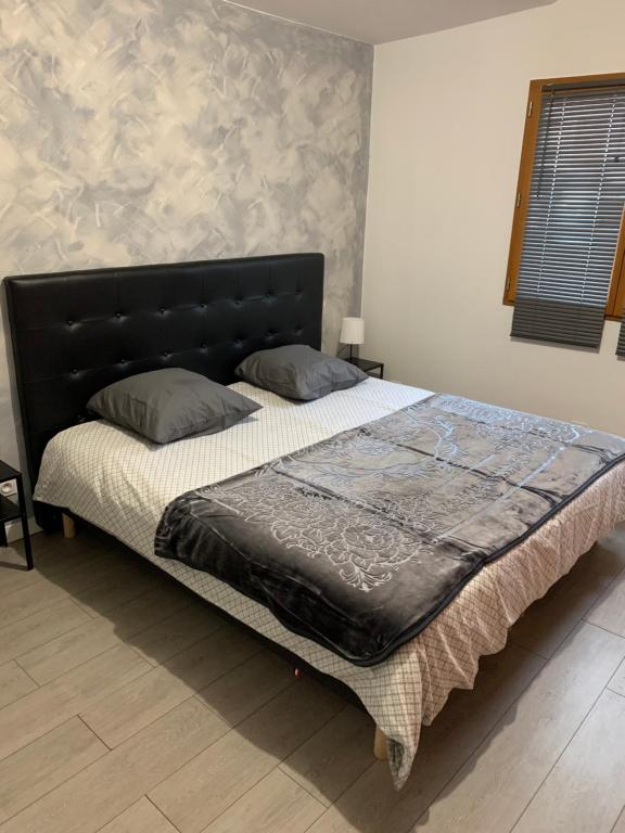 a bed with a black headboard in a bedroom at Appartement équipé pour 5 pers in Vénissieux
