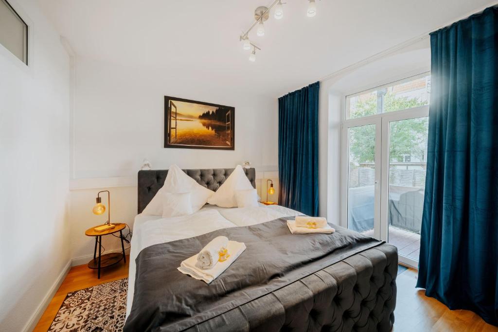une chambre avec un grand lit avec des rideaux bleus dans l'établissement BlissPlace 3 Zi Premium Apartment nahe GETEC Arena mit Kingsize Betten und Balkon, à Magdebourg