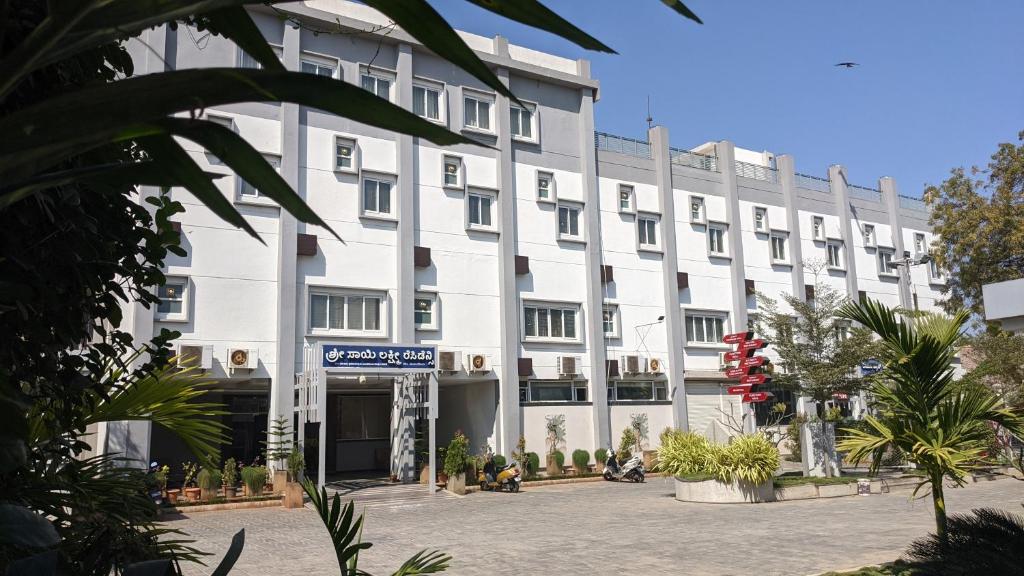 ein großes weißes Gebäude mit Pflanzen davor in der Unterkunft Hotel SSLR ,Gangavathi in Hampi