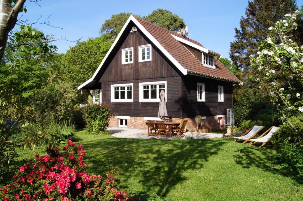 Cette grande maison en bois dispose d'une table dans la cour. dans l'établissement Chalet de Vasterival, à Varengeville-sur-Mer