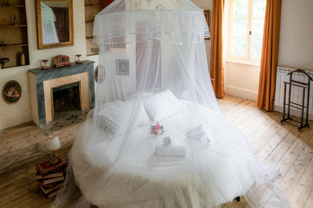 - un lit blanc avec un voile et une cheminée dans l'établissement Chambre d'hôtes insolite lit rond B&B proche Avignon Orange - Château de Sienne Piscine Rivière, à Chusclan