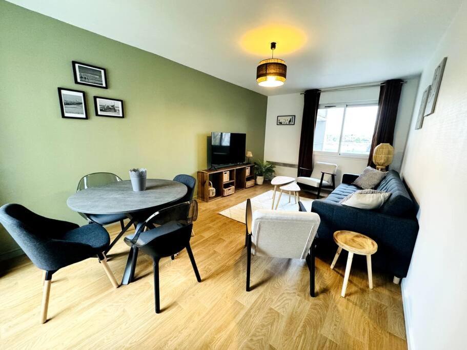 een woonkamer met een bank en een tafel en stoelen bij Bel appartement rénové dans une résidence calme in Caen