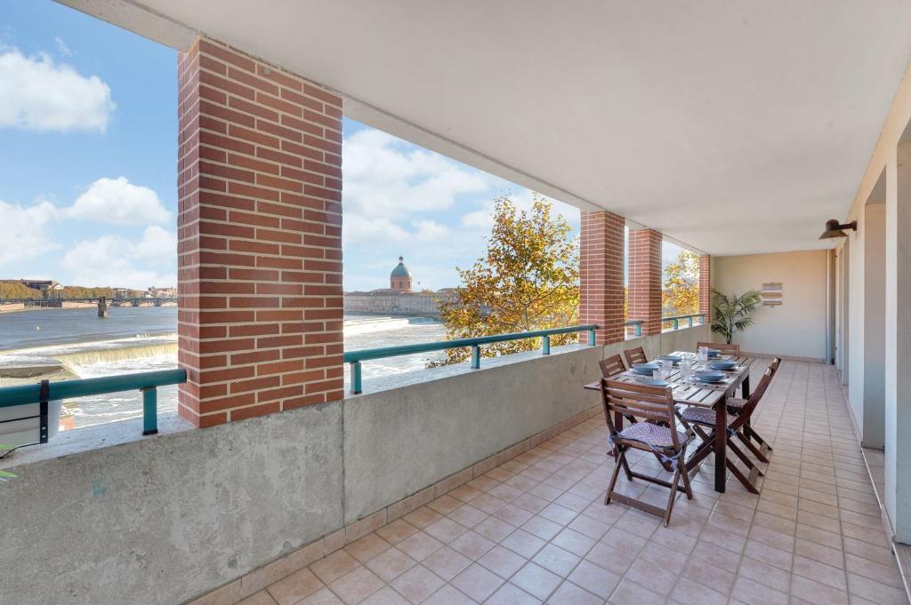 d'un balcon avec une table et des chaises et une vue sur l'eau. dans l'établissement Rio L'Aïga - Superbe terrasse sur Garonne, à Toulouse