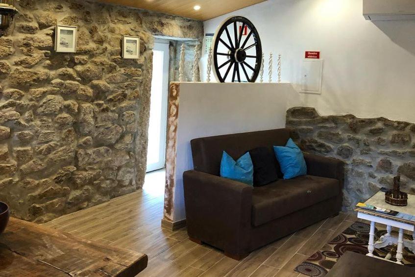 uma sala de estar com um sofá e uma roda na parede em Casas do Lobo em Tarouca