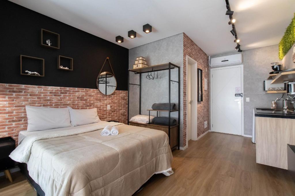 een slaapkamer met een groot bed en een bakstenen muur bij Apartamento 1106 em condomínio de alto padrão in Guarulhos