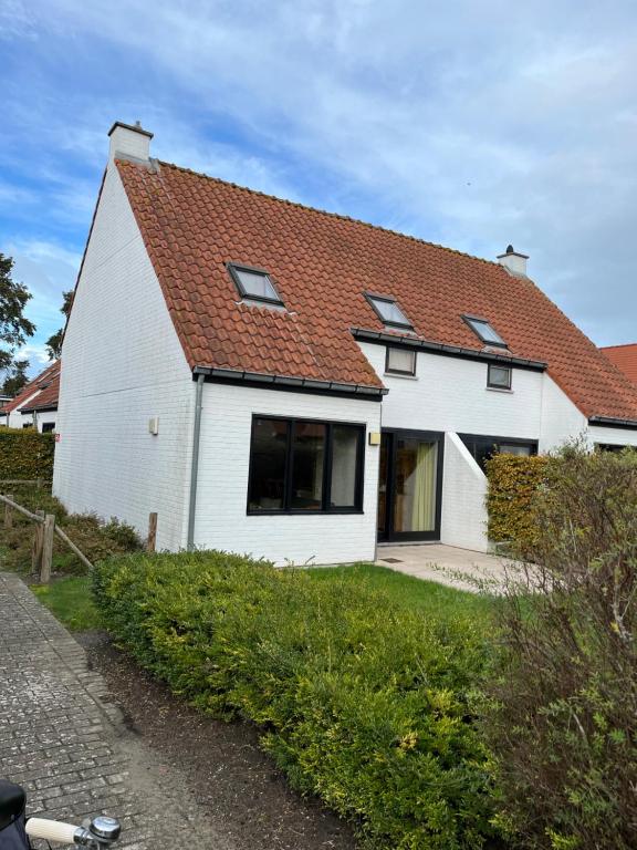 une maison blanche avec un toit rouge dans l'établissement Colibri 9, à Nieuport