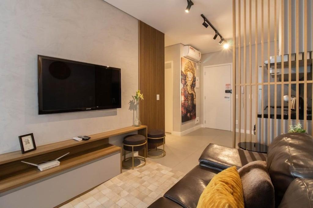 Helbor Patteo 1508 | Loft de luxo في جوارولوس: غرفة معيشة مع أريكة وتلفزيون بشاشة مسطحة