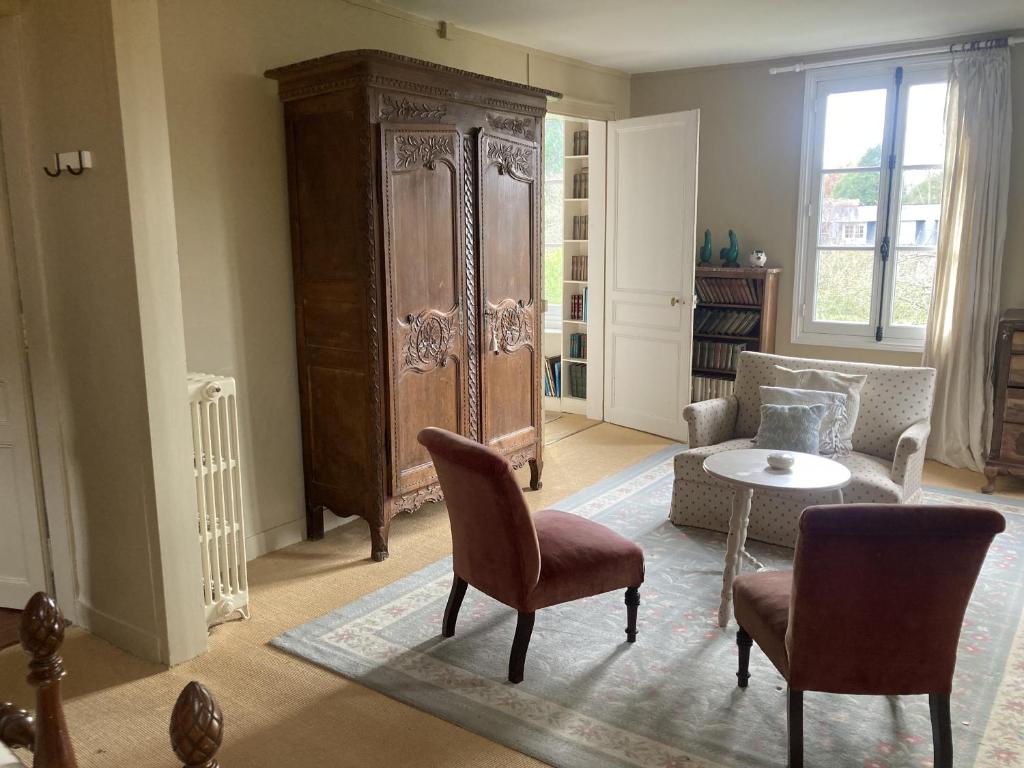 a living room with a large cabinet and chairs at Grand Clos Normand in Varengeville-sur-Mer
