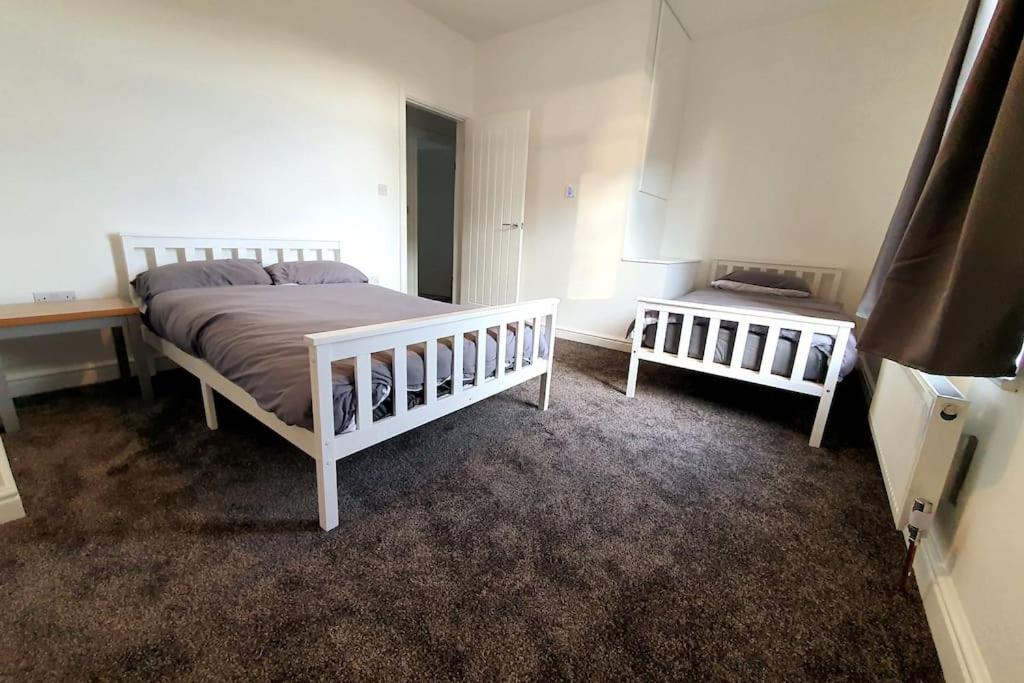 a bedroom with a bed and two cribs at Charming 2BD tranquil stay in Ferryhill, Durham in Ferryhill