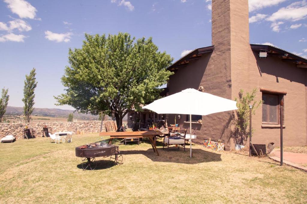 stół piknikowy z parasolem przed budynkiem w obiekcie Posada Punta de Piedra w mieście La Cumbre