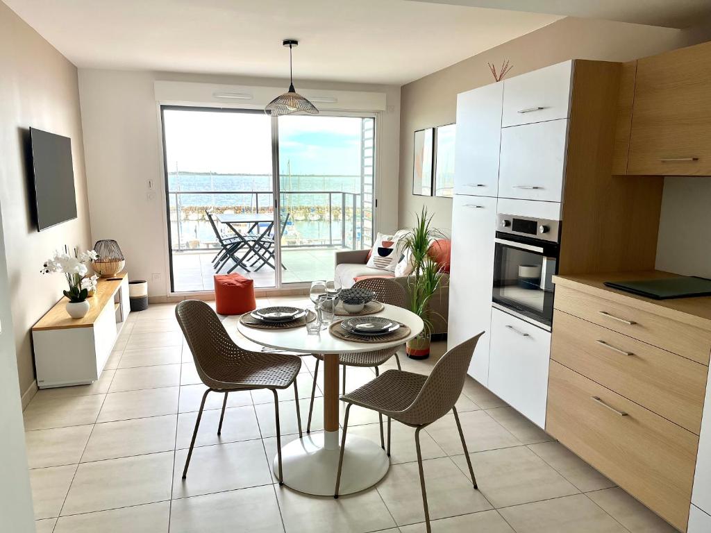 cocina y sala de estar con mesa y sillas en Appartement standing vue étang de Thau, en Marseillan