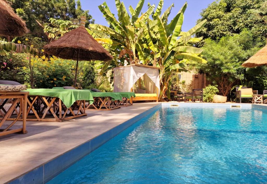 a resort pool with tables and umbrellas and a tent at Ginger Villa Somone in Somone