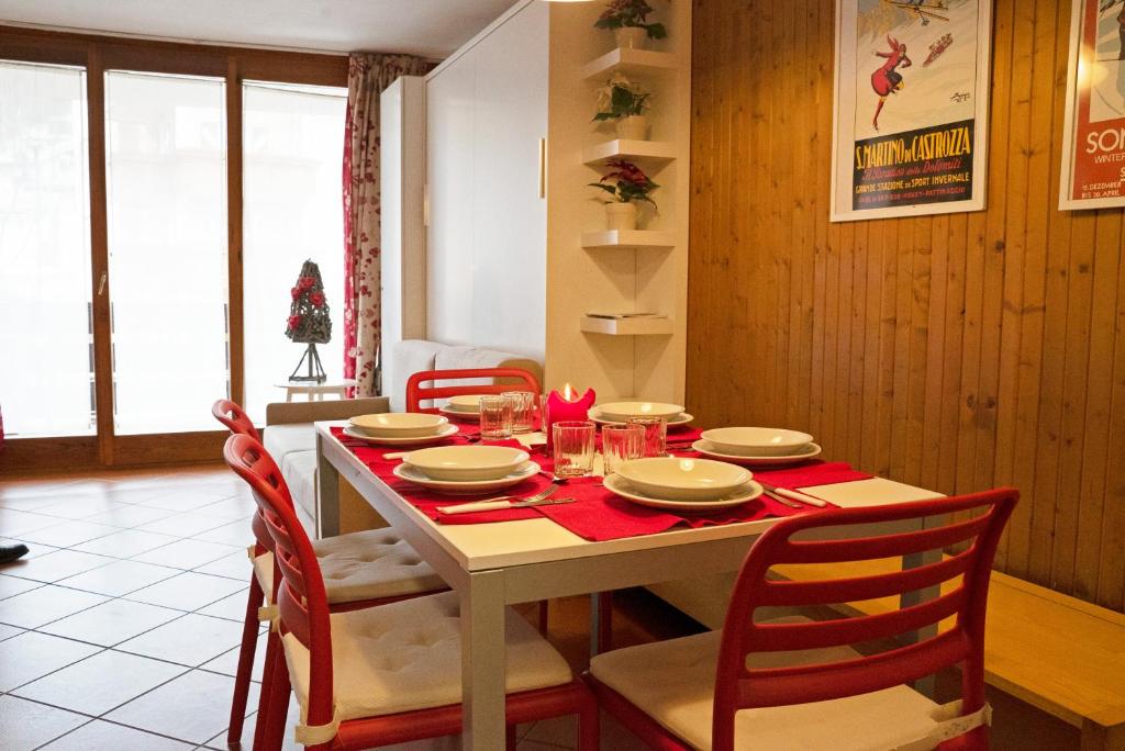 un comedor con una mesa con sillas rojas y un tocador en Le Nasse en San Martino di Castrozza