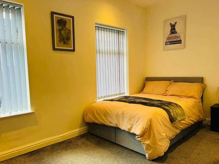 a bedroom with a bed with yellow walls and windows at 4 Bed 4 Bath 6 Guest Lovely home in Stoke on Trent