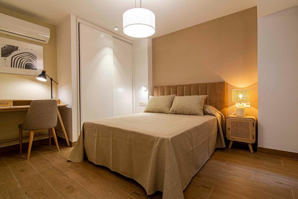 Un dormitorio con una cama grande y un escritorio. en Apartamentos 1 Abril, en Málaga