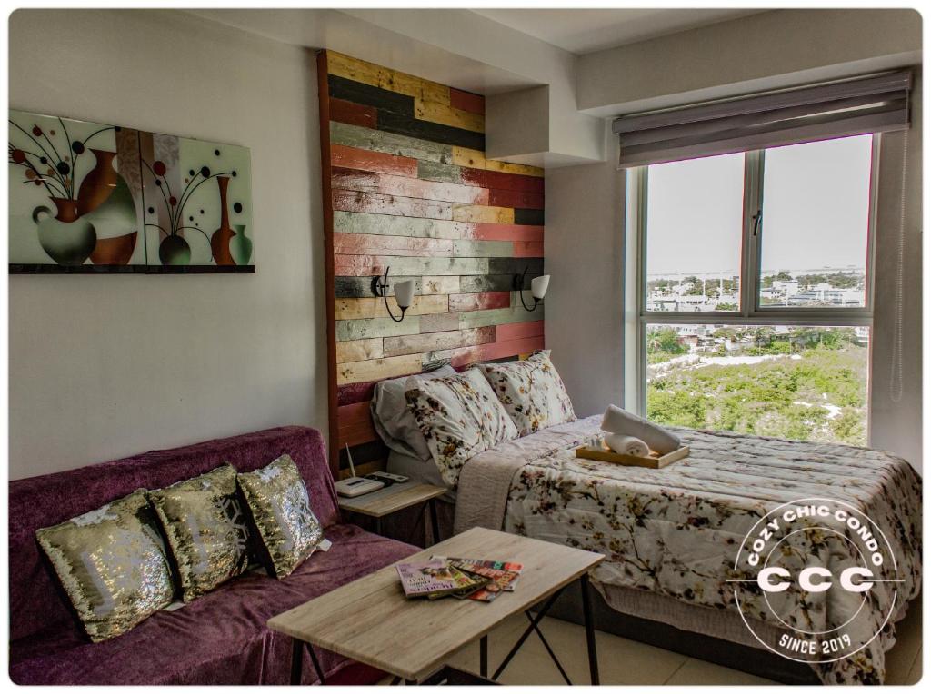 ein Schlafzimmer mit einem Bett, einer Couch und einem Tisch in der Unterkunft Cozy Chic Condotel Avida Towers Sucat in Manila