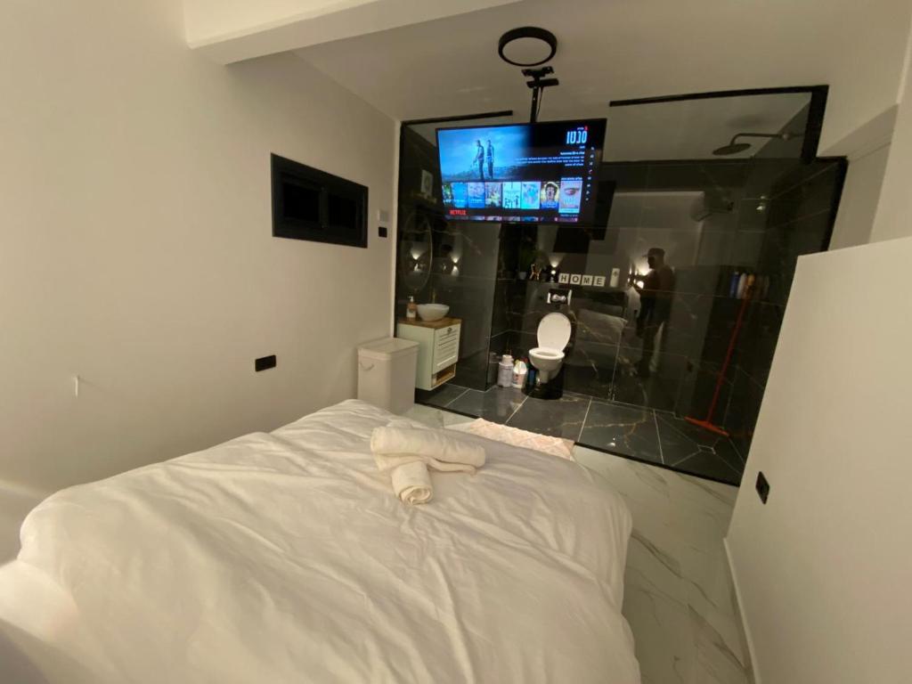 een slaapkamer met een wit bed en een tv aan de muur bij נטלי בעמק Natali in the valley in Bet Sheʼan