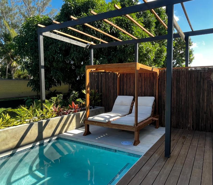 una pérgola y una silla junto a la piscina en Villas Palmar, en Aguadilla