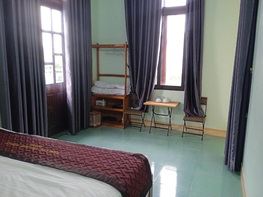 寧平的住宿－Tam Coc Village，卧室配有床、桌子和窗户。