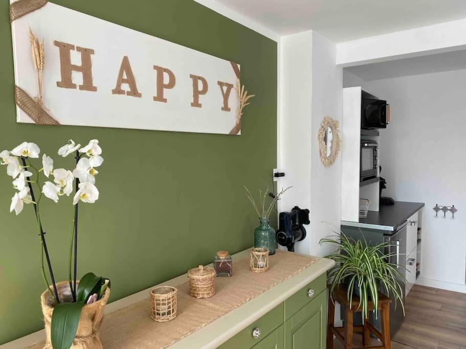 una sala de estar con un cartel feliz en una pared verde en Appartement au gré des bulles, en Cucq