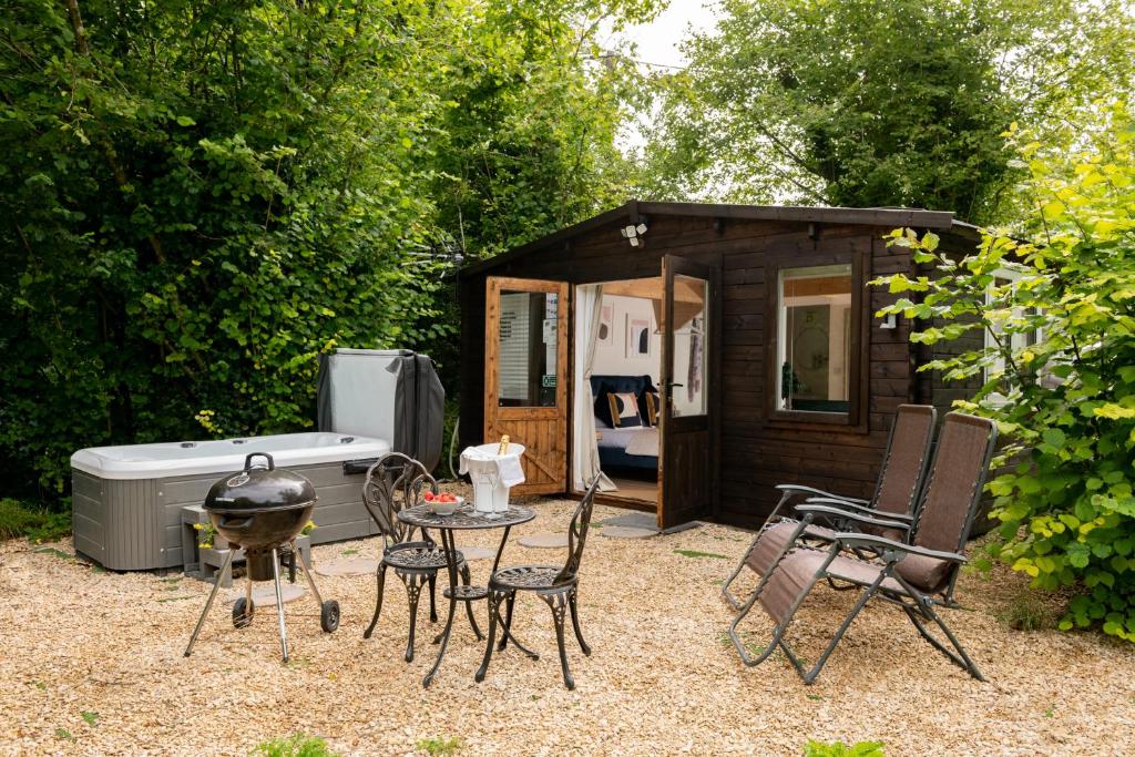 a barbecue grill and chairs in front of a cabin at Copperbeech - Luxury Holiday with Private Hottub in Blandford Forum