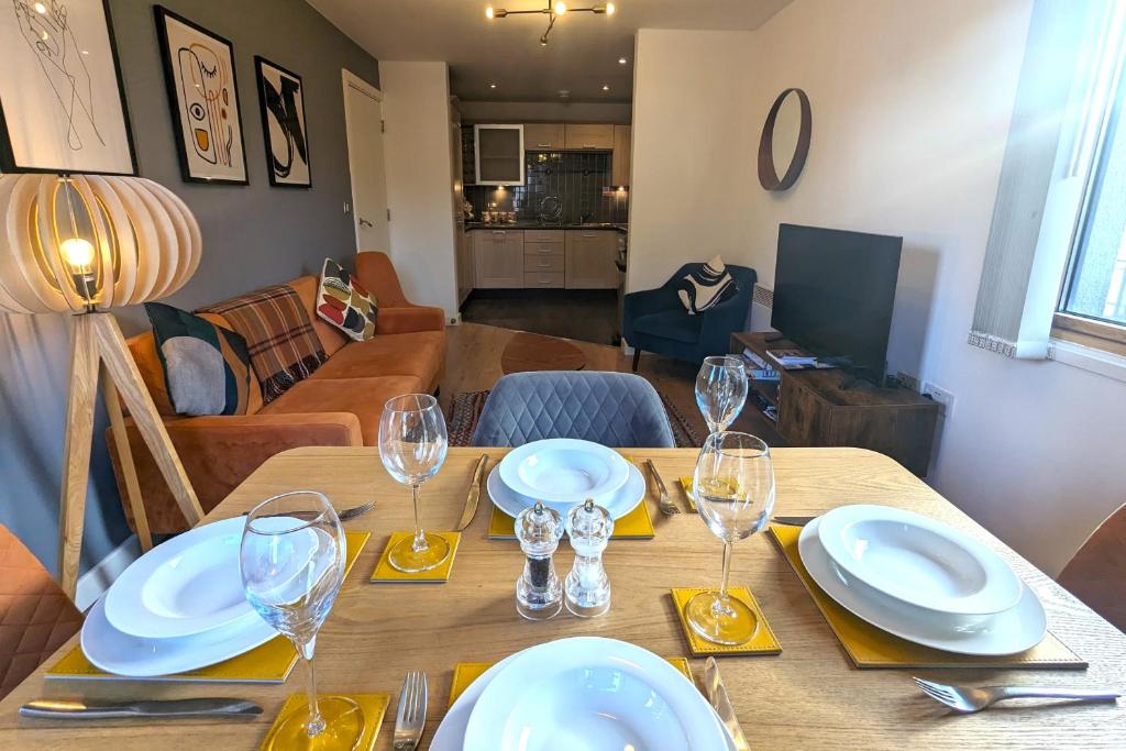 a dining room table with plates and glasses on it at Stunning Modern Coventry City Centre Apartment in Coventry