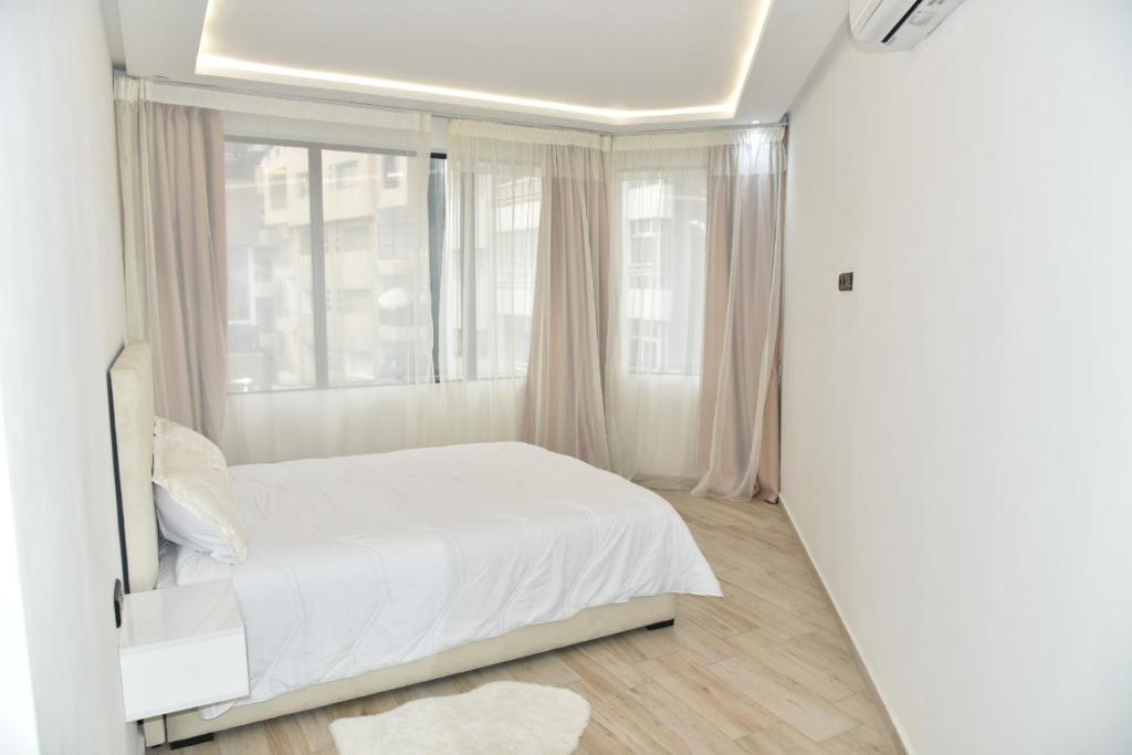 BRAND NEW! 3 Bedroom Apartment in the Heart of Kenitra في القنيطرة: غرفة نوم بسرير ابيض ونافذة