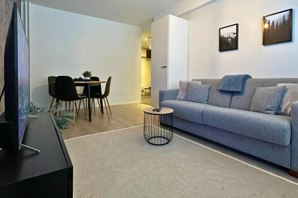 a living room with a blue couch and a table at Pramea Apartments Haapaniemenkatu in Kuopio