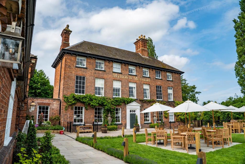 un grand bâtiment en briques avec des tables et des parasols dans l'établissement Mytton and Mermaid - Brunning and Price, à Shrewsbury