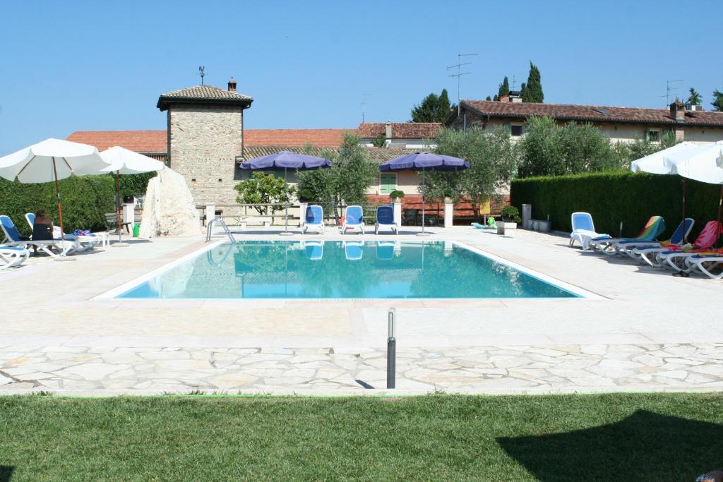 a swimming pool in a yard with chairs and umbrellas at Cà Donzella in Lazise