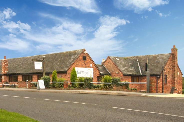 a brick building on the side of a street at The mill wheel in Hartshorne