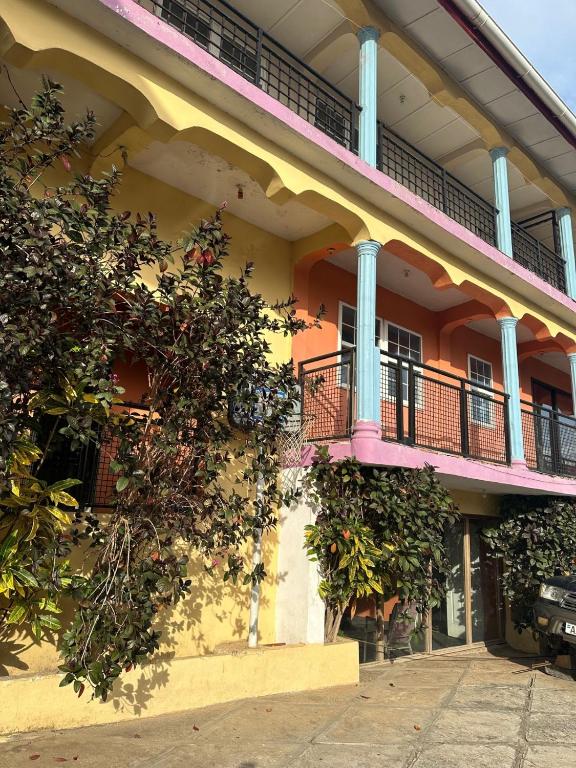 a yellow building with a pink balcony and plants at STONE CASTLE HOTEL in Freetown