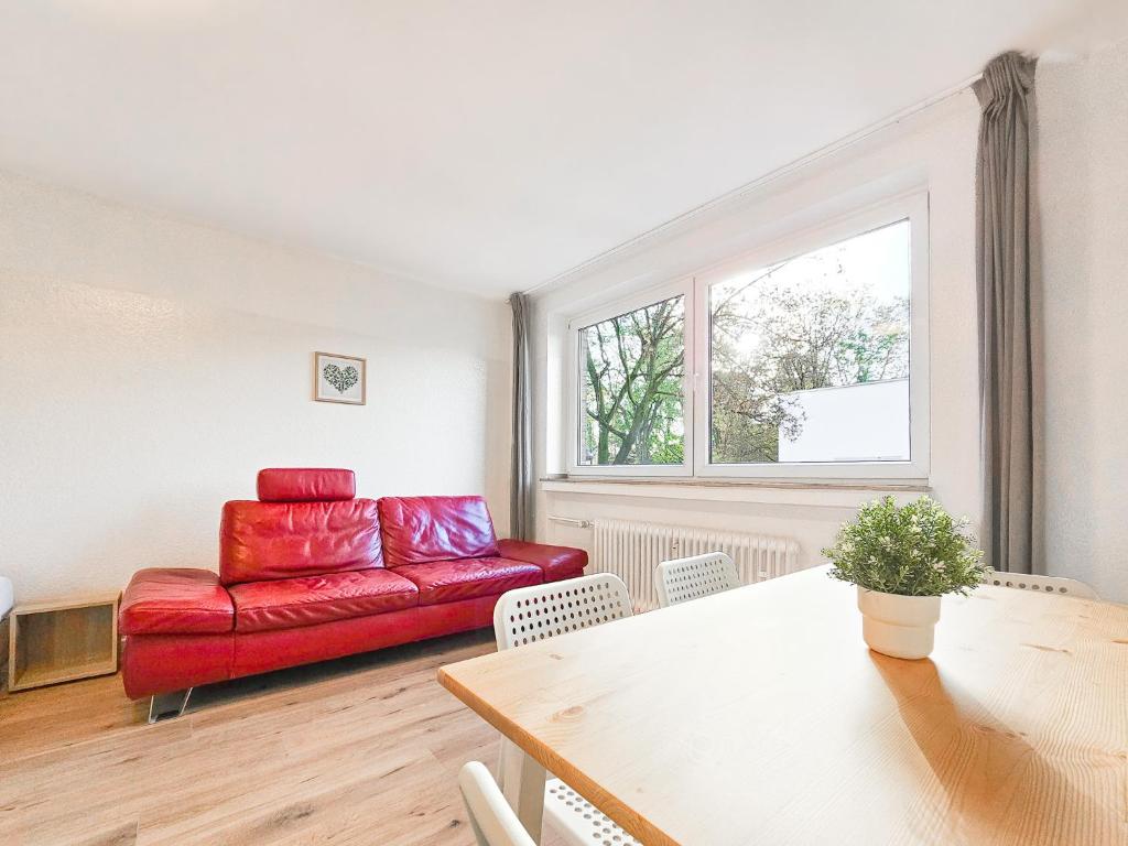 salon z czerwoną kanapą i stołem w obiekcie RAJ Living - 2 or 3 Room Apartments - 15 Min zur Messe DUS & 10 Min Old Town DUS w mieście Düsseldorf