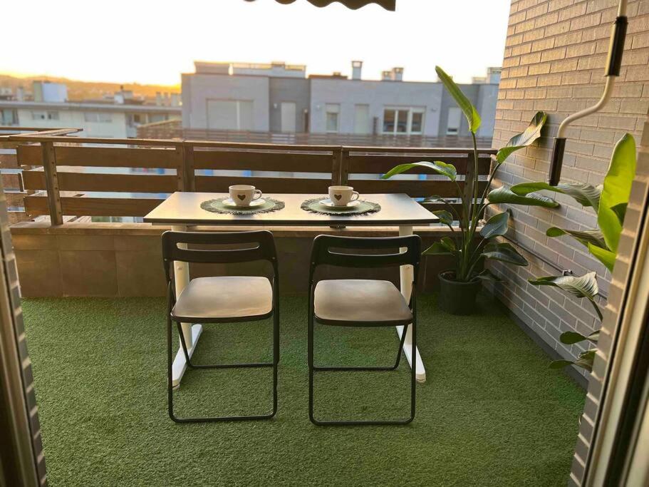 una mesa y 2 sillas sentadas en un balcón en Luminoso ático con terraza en Santander