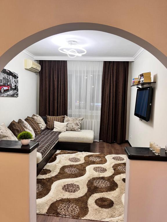 uma sala de estar com um sofá e uma televisão em Уютная квартира Курмангазы 5 em Atyrau
