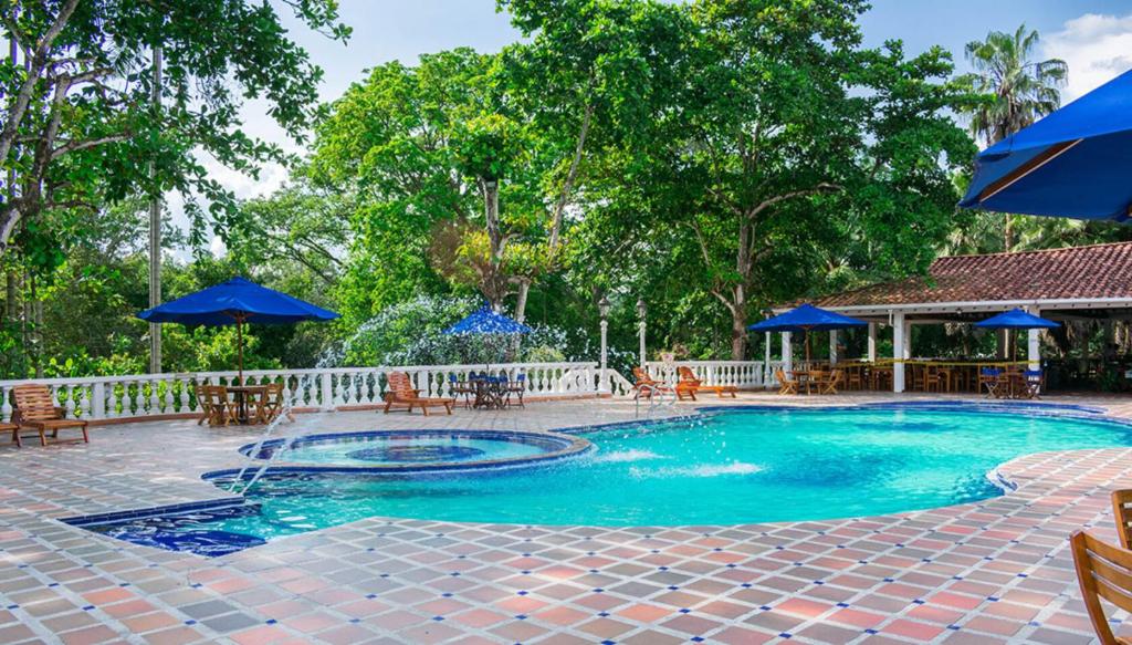 Hotel Posada San Sebastian في سان جيرونيمو: مسبح بمظلات زرقاء وطاولات وكراسي