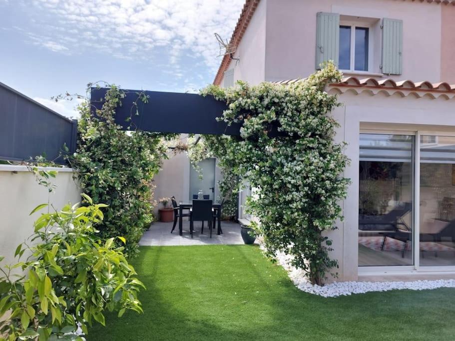 un jardin avec une pergola et de la pelouse verte dans l'établissement Maison entière Redessan, à Redessan