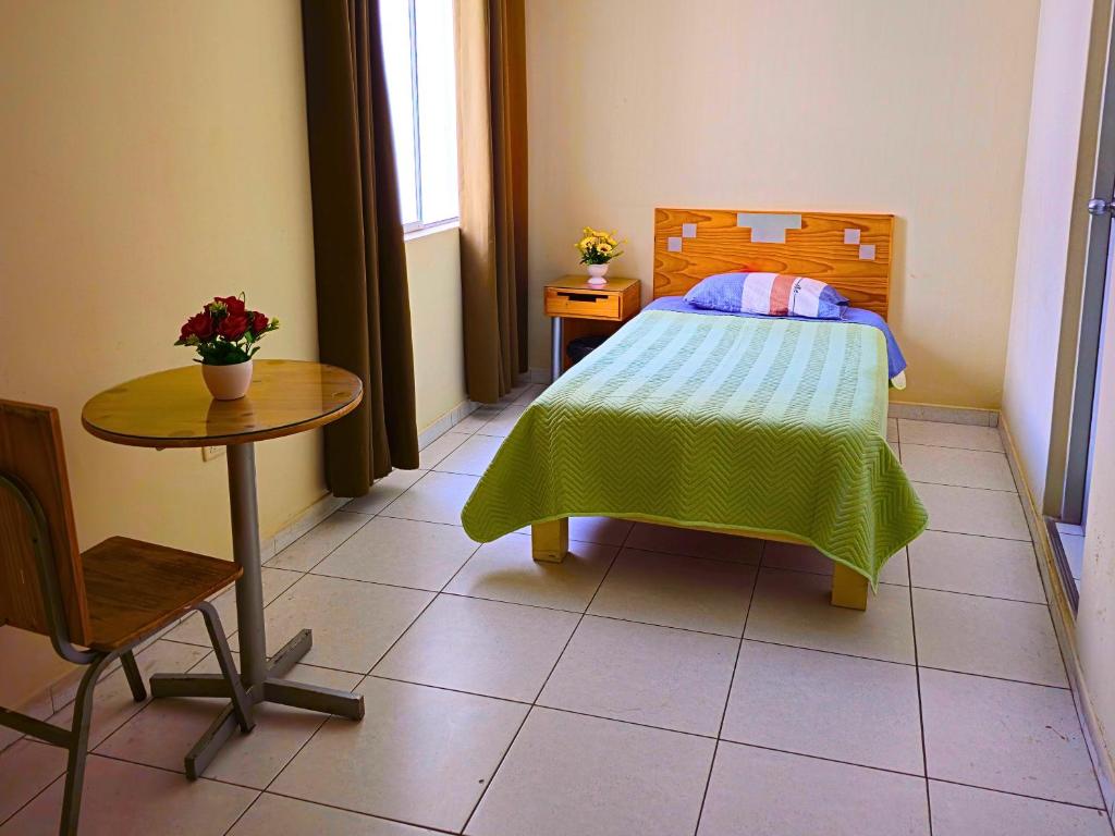 a small bedroom with a bed and a table at Hostal Santa Barbara in Ilo