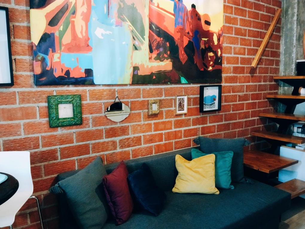 a brick wall with a green couch with colorful pillows at El Pozo-Villalobos Suite in Madrid