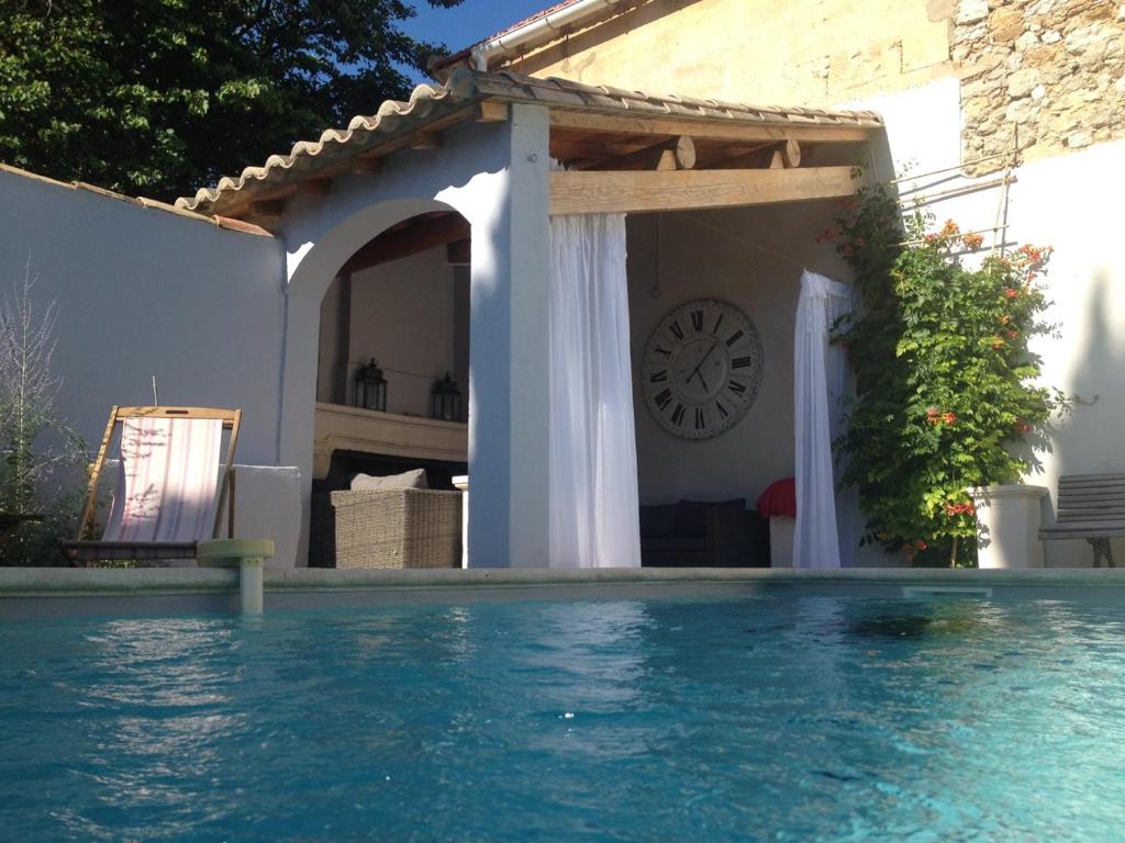 a house with a clock and a swimming pool at Moulin des Calans in Maussane-les-Alpilles