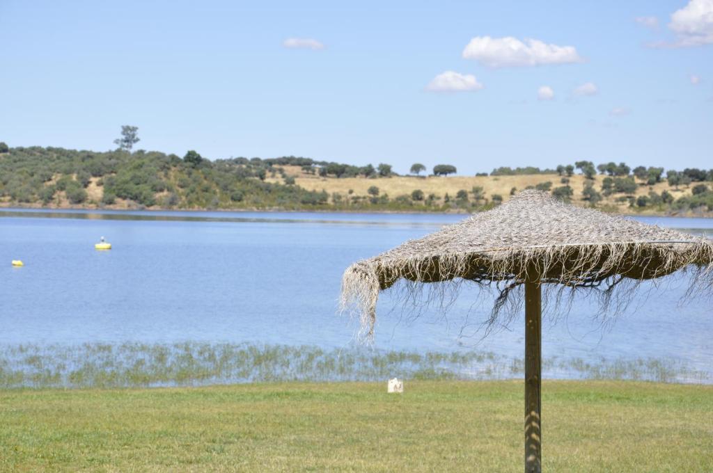 a straw umbrella in front of a body of water at Cruceros Alqueva in Cheles
