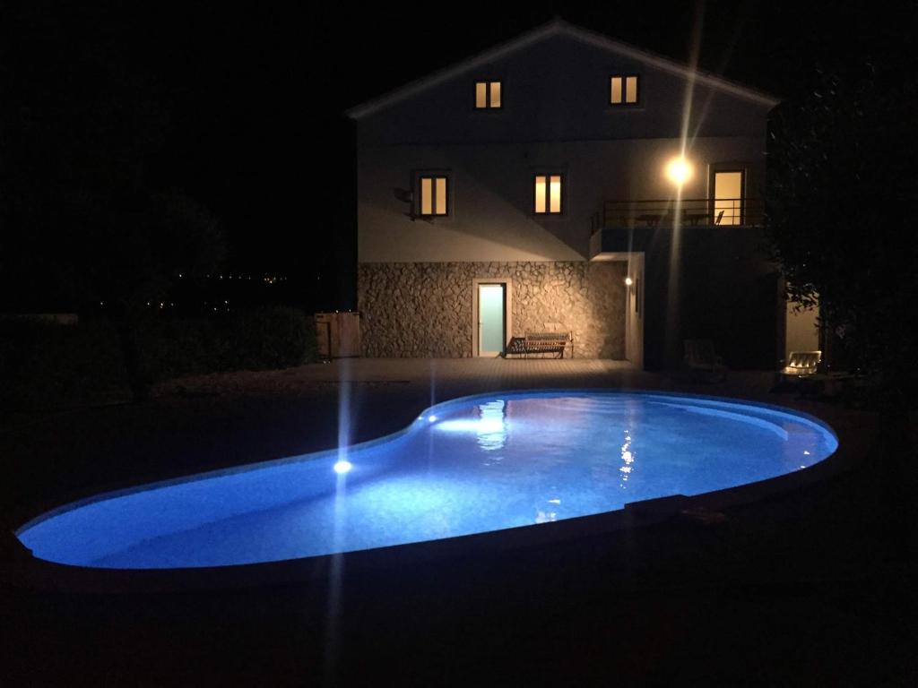 una gran piscina azul frente a una casa por la noche en Casa de Sandoeira, en Rego da Murta