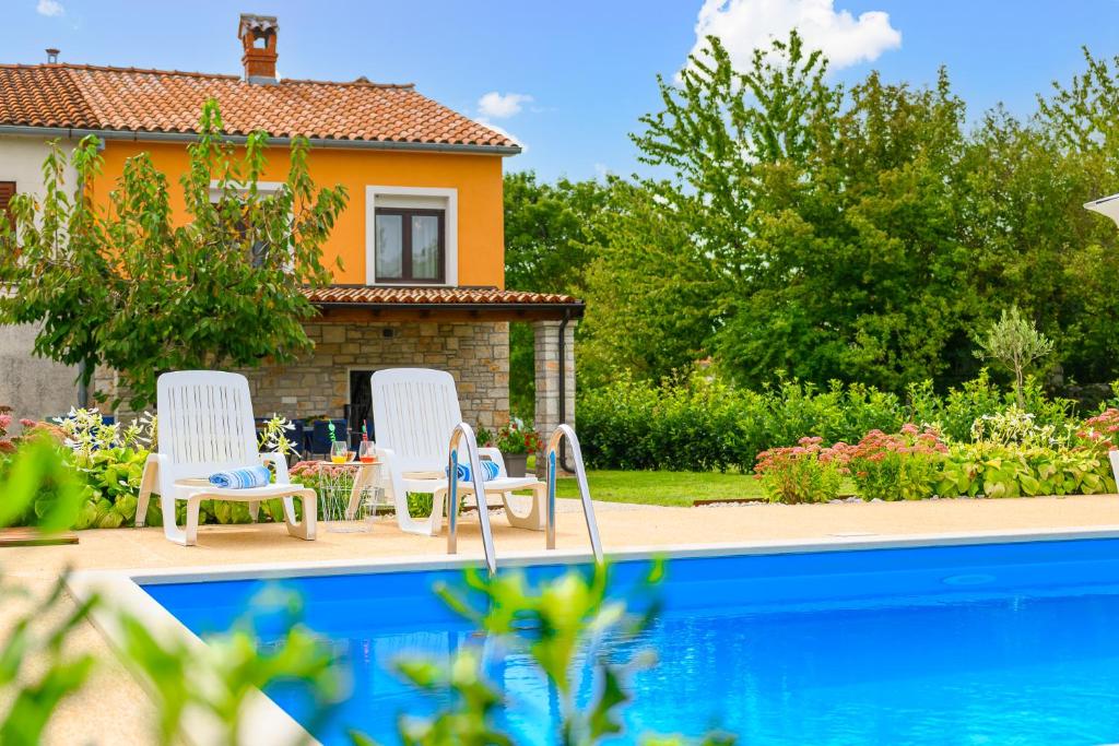 une maison avec deux chaises et une piscine dans l'établissement Holiday Apartment Ariella, à Križanici